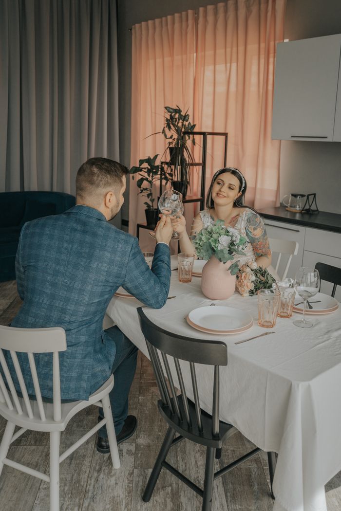 A couple enjoying a romantic dinner, toasting with wine glasses at an elegant indoor setting.